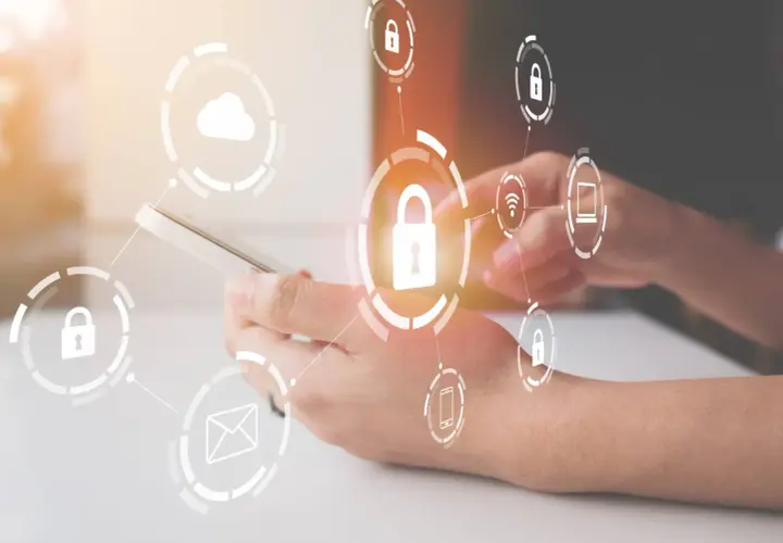 Manos sujetando un teléfono con iconos de seguridad y dispositivos de almacenamiento conectados, simbolizando la protección de datos.