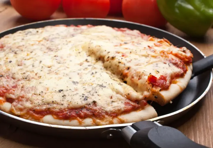 Pyszna pizza z patelni, z ciągnącym się serem i aromatycznymi ziołami, gotowa do podania.