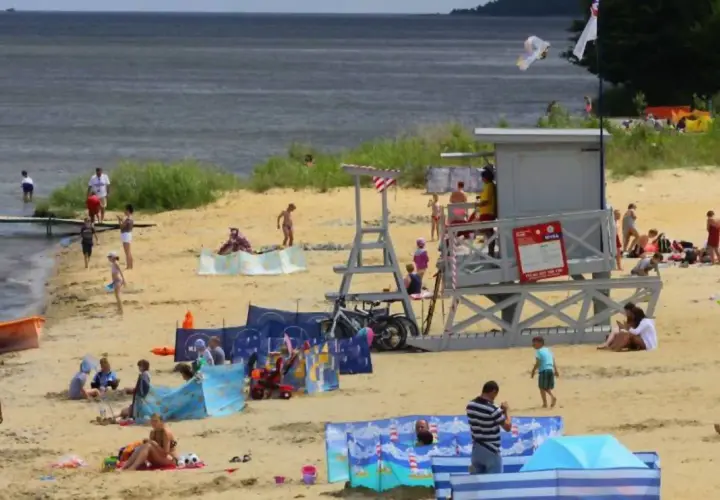 Słoneczna puck plaża tętni życiem. Ludzie opalają się, kąpią i bawią, tworząc radosną atmosferę.