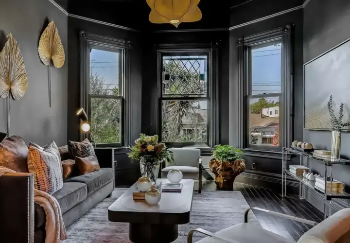 Elegancki salon w stylu wiktoriańskim. Ciemne ściany, ozdobne okna i stylowe meble tworzą przytulną atmosferę.