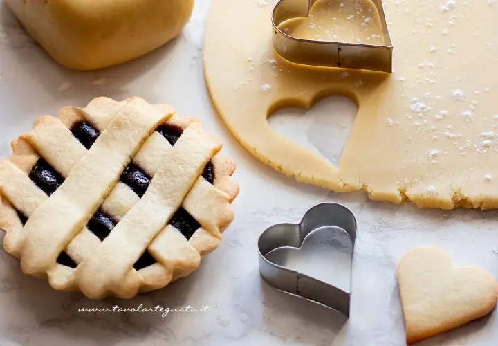 Pasta frolla pronta per essere infornata. La temperatura di cottura è fondamentale per ottenere un risultato perfetto. Cuoricini di frolla e crostata con marmellata.