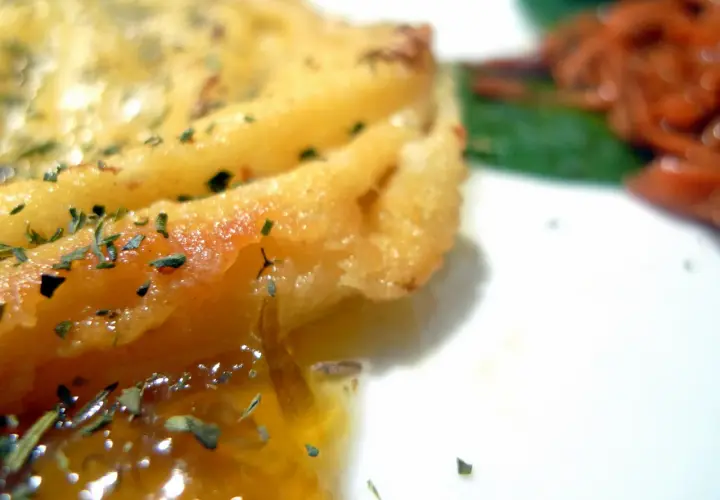 Queso provolone dorado y burbujeante, con hierbas, listo para servir. Descubre como hacer provolone a la plancha.