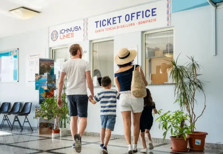 Famiglia in coda all'ufficio biglietti per la Corsica con bambini. L'avventura inizia qui!