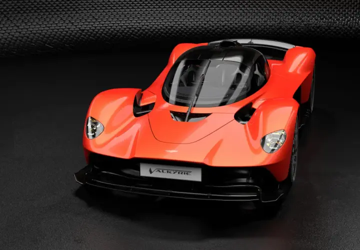Pomarańczowy Aston Martin Valkyrie, supersamochód o futurystycznym designie, prezentuje swoje aerodynamiczne linie na ciemnym tle.
