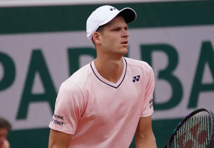 Hubert Hurkacz w różowej koszulce i białej czapce z logo Yonex, gotowy do gry na korcie.