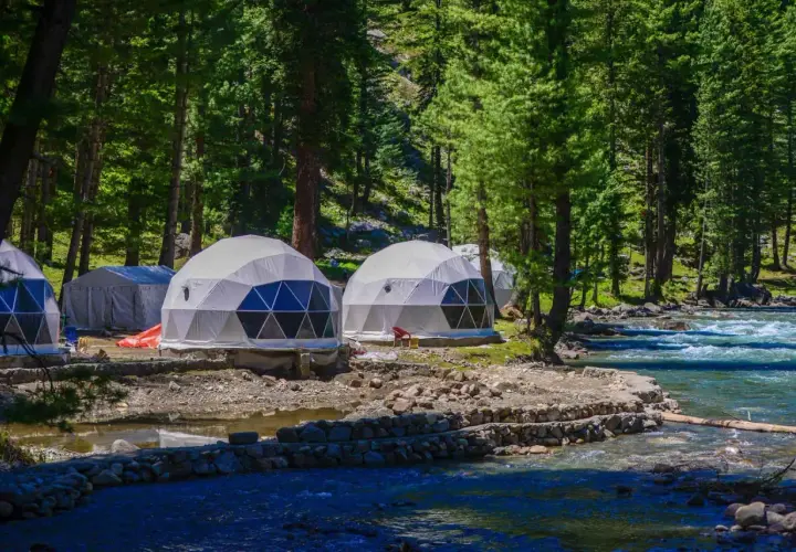 Glamping nad jeziorem: kopuły noclegowe w otoczeniu lasu, blisko rwącej rzeki.