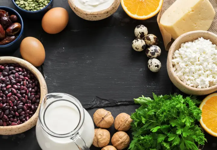 Vielfalt an calcium lebensmittel: Milch, Käse, Joghurt, Eier, Bohnen, Datteln, Nüsse, Orangen und Petersilie.