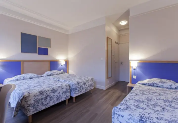 Pokój hotelowy z trzema łóżkami, idealny dla rodziny szukającej odpowiedzi, gdzie najlepiej nocować w Paryżu.