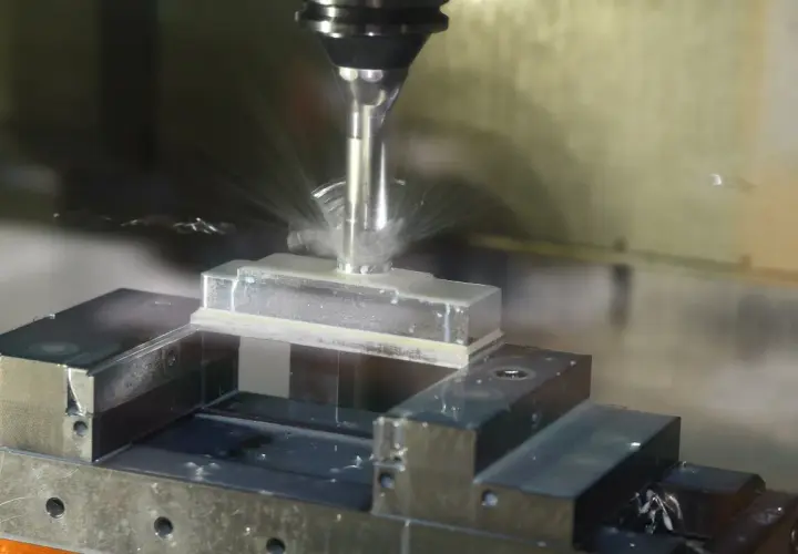 Precyzyjne frezowanie aluminium na maszynie CNC. Chłodziwo rozpryskuje się wokół obrabianego elementu.