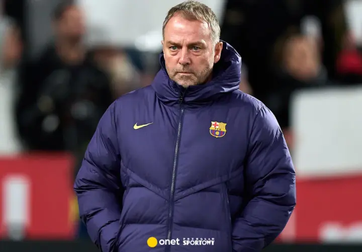 Zamyślony trener Barcelony w granatowej kurtce z herbem klubu.