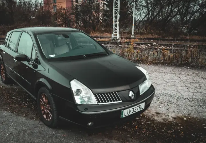Czarny Renault Vel Satis z miedzianymi felgami stoi przy torach kolejowych.