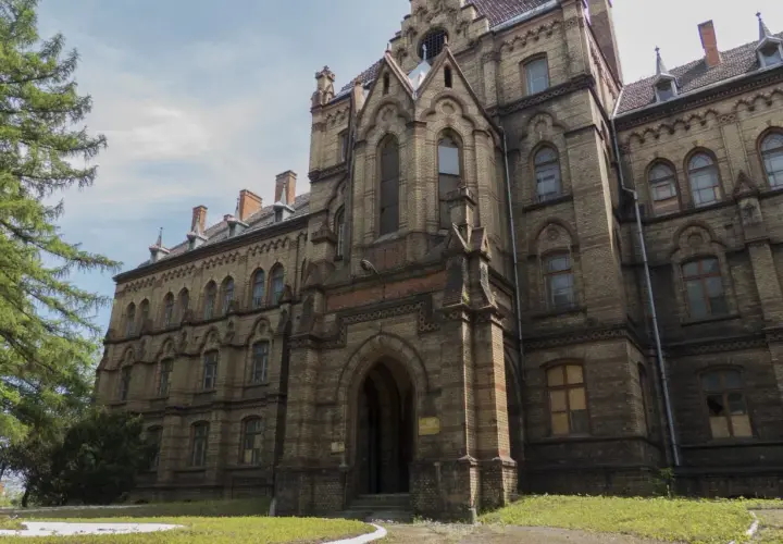 Mokrzeszów pałac, monumentalna budowla z cegły, z charakterystycznymi łukami i wieżyczkami, otoczona zielenią.