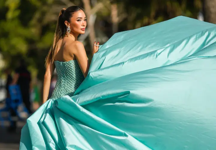 Elegante Frau in einem türkisfarbenen Ballkleid, das den **black tie dress code** perfekt verkörpert. Ihr Kleid weht im Wind.
