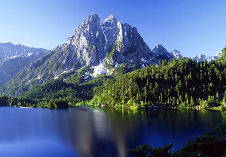 El estany de Sant Maurici, un lago alpino rodeado de bosques de pinos y picos nevados, refleja la majestuosidad de la naturaleza.