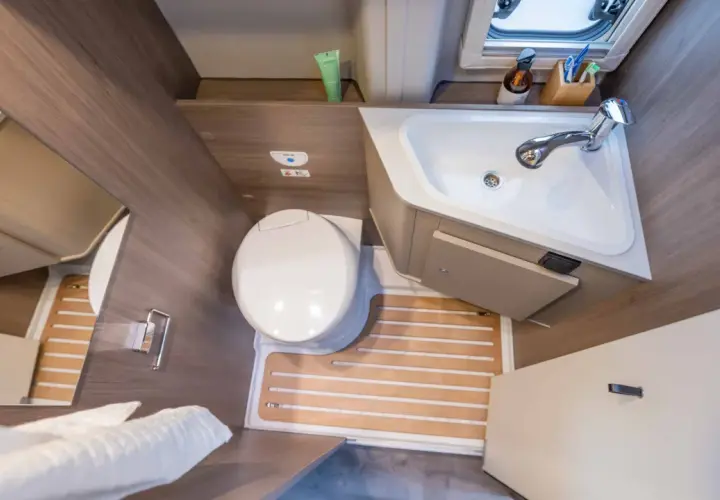 Salle de bain arrière de camping-car : toilette, lavabo et douche intégrée. Pratique pour les voyages.