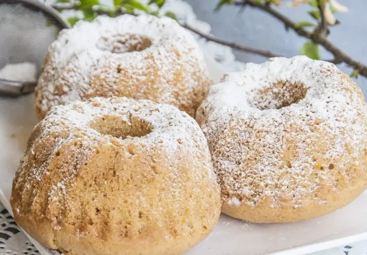 Trzy puszyste muffinki piaskowe posypane cukrem pudrem, gotowe do podania.