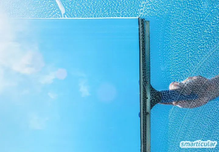 Fensterputzen mit Glycerin: Ein klarer Blick auf den blauen Himmel, während eine Hand mit einem Abzieher über das seifige Glas gleitet.