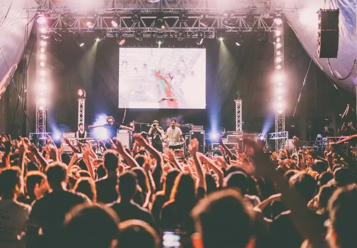 Koncert australijskiego zespołu rockowego. Tłum szaleje, ręce w górze, światła sceniczne.
