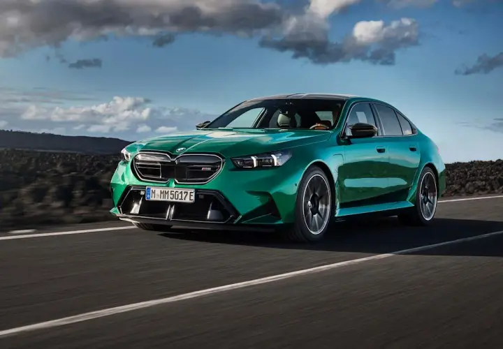 Zielony BMW M5 na drodze, chmury na niebie. Sprawdź aktualną bmw m5 cena i możliwości tego sportowego sedana.