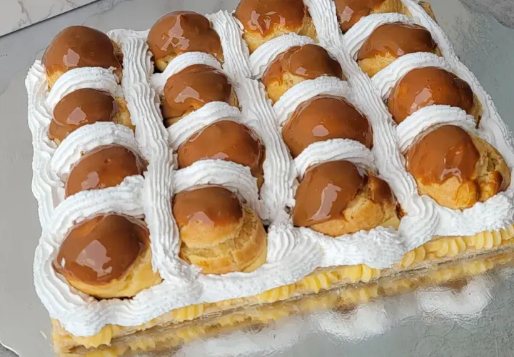 Deliciosa torta rellena de crema pastelera y cubierta con profiteroles bañados en dulce de leche y decorada con crema chantilly.