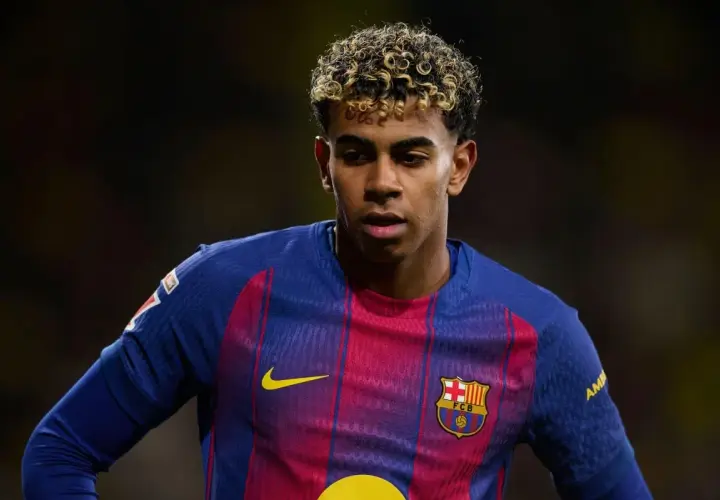 Młody piłkarz Lamine Yamal w koszulce FC Barcelony, z charakterystyczną fryzurą i skupionym spojrzeniem.