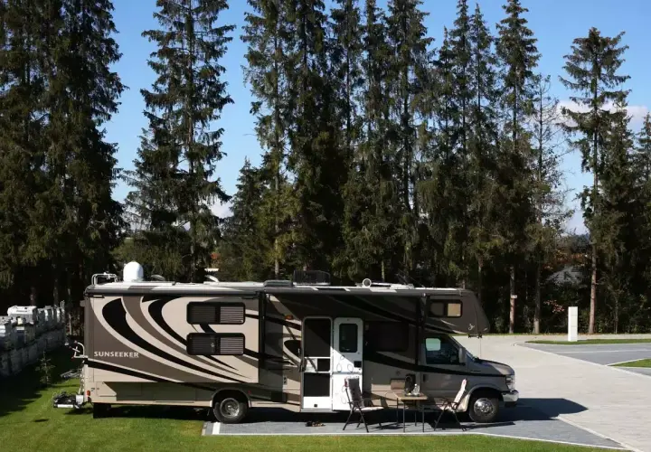 Kamper Sunseeker zaparkowany na campingu Gorący Potok, otoczony wysokimi sosnami.