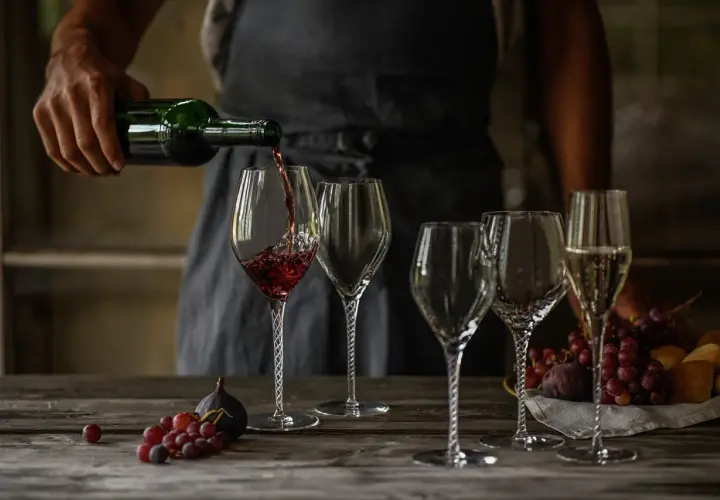 Skutki napowietrzania wina (dekantacja) widoczne podczas przelewania do karafki. Wino w kieliszku, obok winogrona i figi.