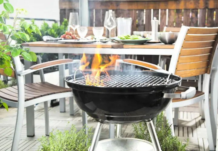 La grille bbq est prête pour un festin en plein air. Des flammes dansent sur les braises, promettant des saveurs estivales. La table est dressée, invitant au partage.