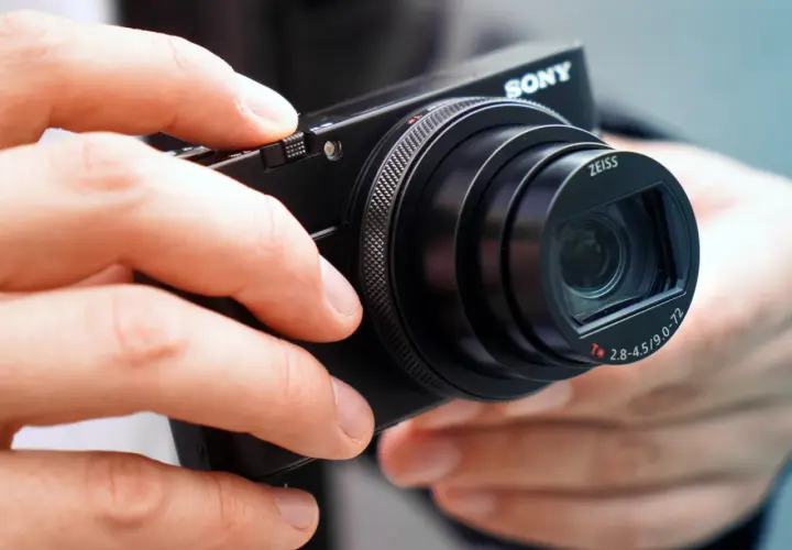 Dłonie trzymają aparat Sony RX100 VII z obiektywem Zeiss.