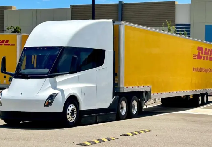 Biały Tesla Semi z żółtą naczepą DHL stoi na parkingu.