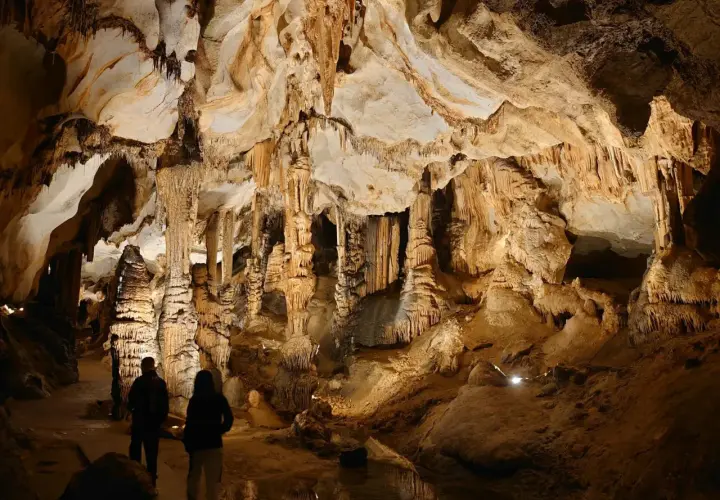 Dwie osoby zwiedzają imponujące jaskinie w Polsce, podziwiając stalaktyty i stalagmity.