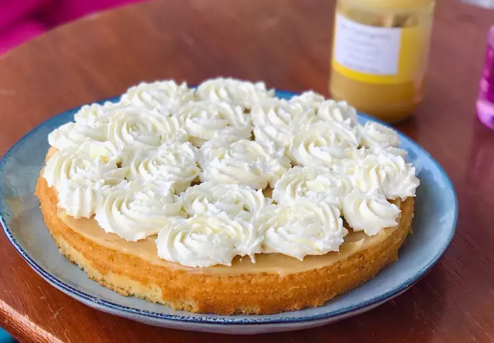 Tårta med fluffig grädde och en gyllene botten, troligen med smak av lemon curd. En burk syns i bakgrunden.