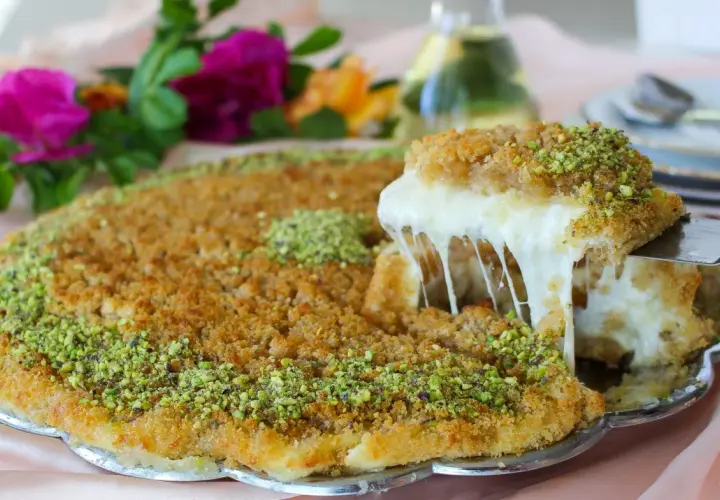 En bit krämig kunafa med smält ost som dras ut, toppad med pistagenötter. Ett läckert kunafa recept att prova!