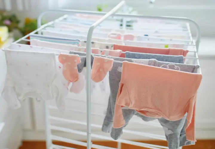 Suszenie ubranek dla noworodka na suszarce. Czy trzeba prasować ubranka dla noworodka? Delikatne body i skarpetki schną, czekając na maluszka.