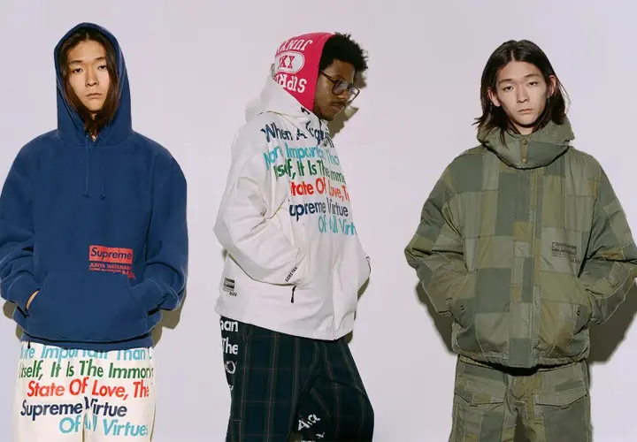 Trzech mężczyzn w ubraniach z kolekcji Junya Watanabe x Supreme. Jeden w granatowej bluzie, drugi w białej kurtce z tekstem, trzeci w zielonej, patchworkowej kurtce.