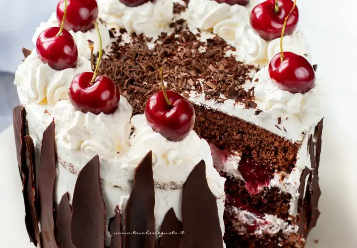 Una fetta di foresta nera torta, con panna montata, ciliegie e scaglie di cioccolato.