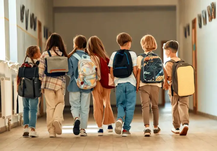Dzieci z plecakami idą korytarzem. Czas na wystawienie ocen na 1 semestr!