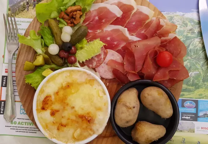 Assiette généreuse de charcuterie, fromage gratiné, pommes de terre et crudités, un vrai plat savoyard pour les gourmands.