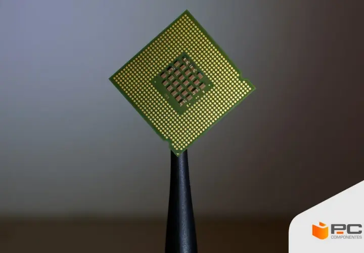 Procesador Intel Core i5, con sus pines dorados y el chip central visible, sostenido por una herramienta.