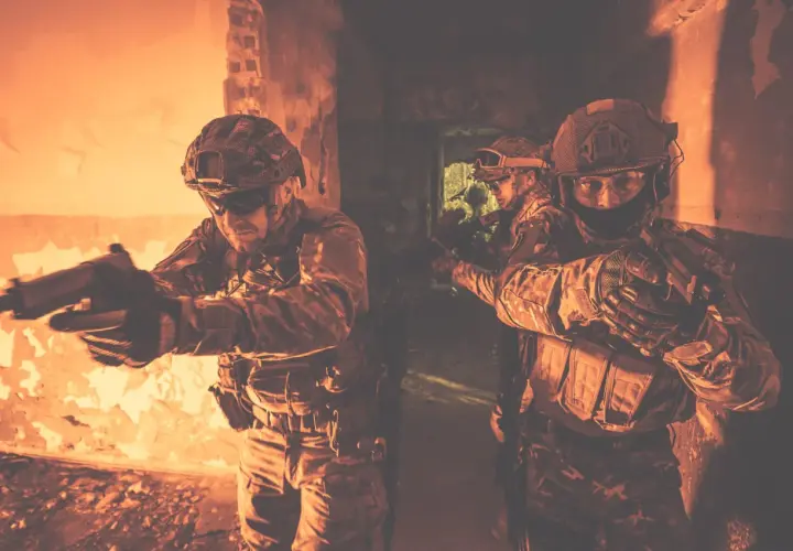Żołnierze w taktycznym kamuflażu, z bronią w rękach, ćwiczą **CQB co to** jest walka w bliskim kontakcie w ciasnych pomieszczeniach.