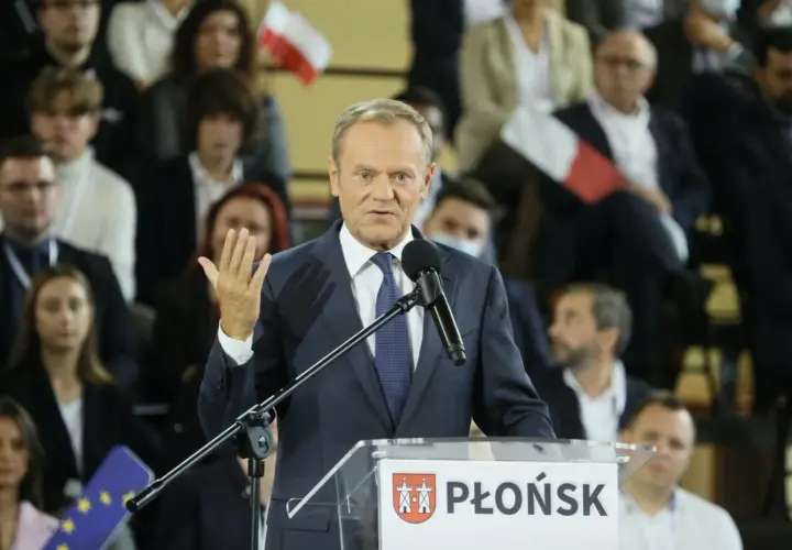 Donald Tusk przemawia na konwencji po w Płońsku. W tle widzowie z polskimi flagami.