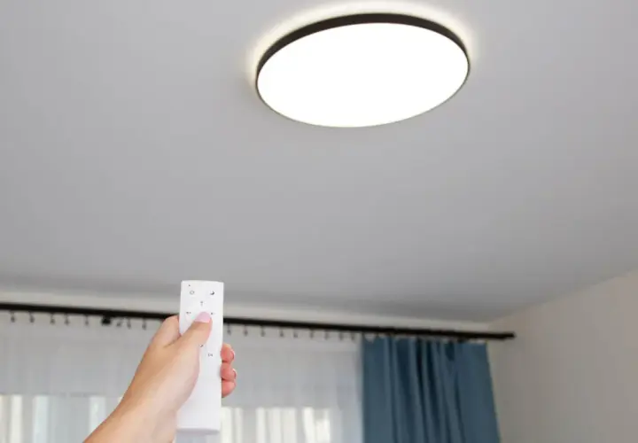 Mano con control remoto ajustando las lámparas led techo.