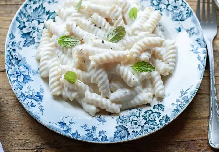 Fusilli conditi con una cremosa salsa alla ricotta, guarniti con foglie di menta fresca. Un piatto semplice e gustoso.