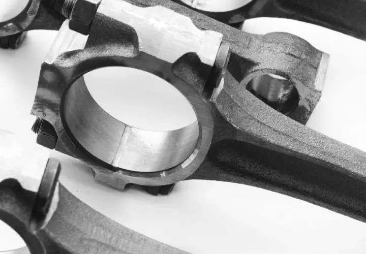 Primer plano de bielas de coche, componentes esenciales que conectan el pistón al cigüeñal, permitiendo el movimiento rotatorio del motor.