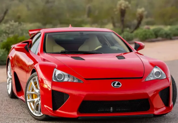Czerwony Lexus LFA z żółtymi zaciskami hamulcowymi, zaparkowany na tle pustynnego krajobrazu.