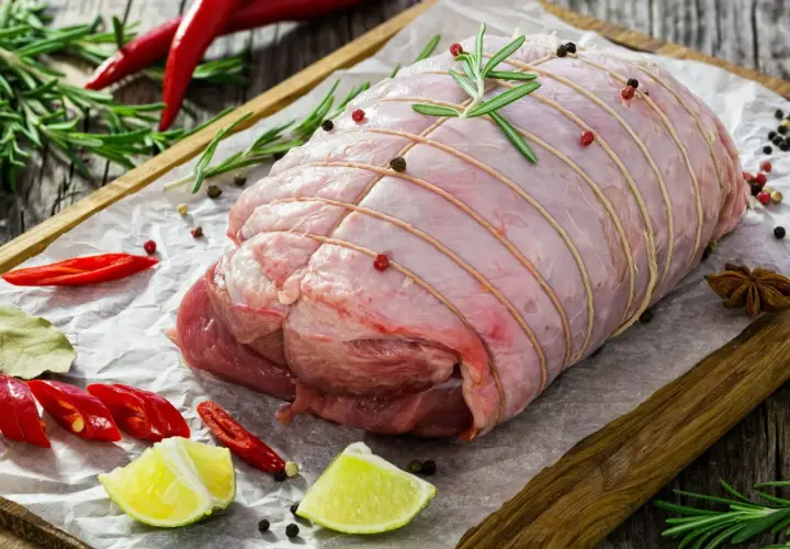 Surowa rolada z indyka, związana sznurkiem, z dodatkiem rozmarynu, pieprzu, chili i limonki, czeka na pieczenie.