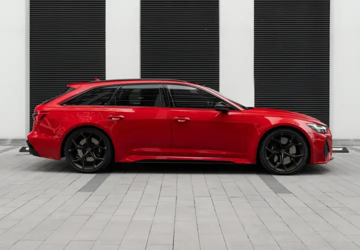 Czerwone Audi RS6 Avant na czarnym tle z białymi pasami. Zastanawiasz się nad audi rs6 cena?