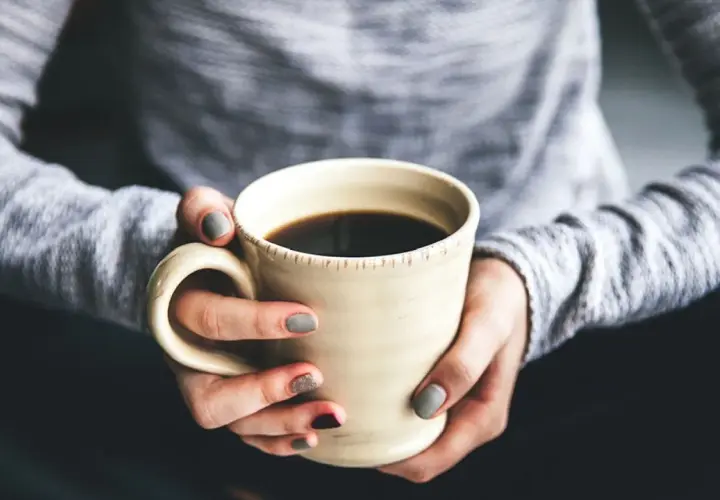 Dłonie trzymają kubek z kawą. Chcesz wiedzieć, jak zrobić kawę rozpuszczalną Nescafé? To proste!