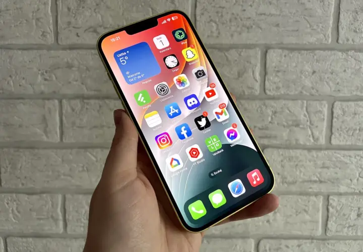 Złoty iPhone z widokiem na ekran główny, gdzie widać aplikacje takie jak pogoda, kalendarz, zdjęcia, YouTube, Gmail. Idealny do codziennej komunikacji i rozrywki, a także do wymiany informacji.