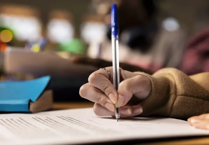 Dłoń pisze długopisem na papierze, przygotowując serdeczne życzenia po angielsku.